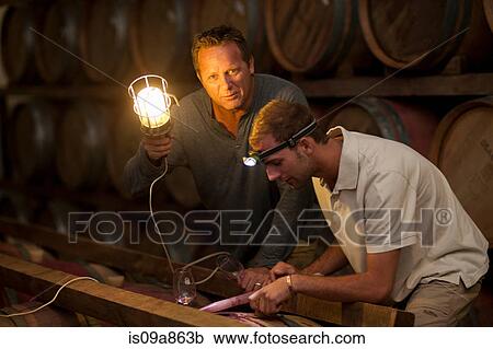 Stock Image - Checking wine aging in barrels. Fotosearch