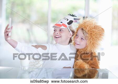 Stock Photography - Children taking pictures of themselves with smartphone. Fotosearch