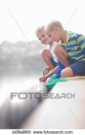 Stock Photograph - Close up of two young boys fishing on pier. Fotosearch