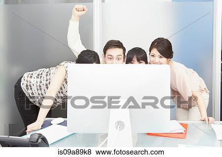 Colleagues looking at computer monitor, man punching the air View Large Photo Image Stock Photo - Colleagues looking at computer monitor, man punching the air. Fotosearch