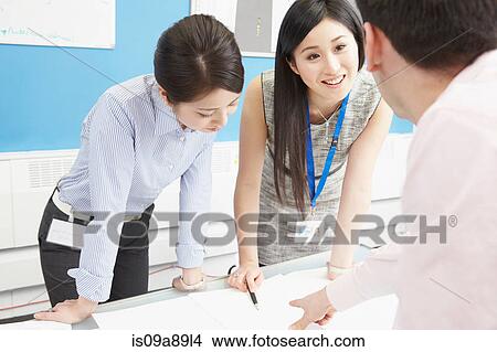 Colleagues working at desk with paperwork View Large Photo Image Picture - Colleagues working at desk with paperwork. Fotosearch