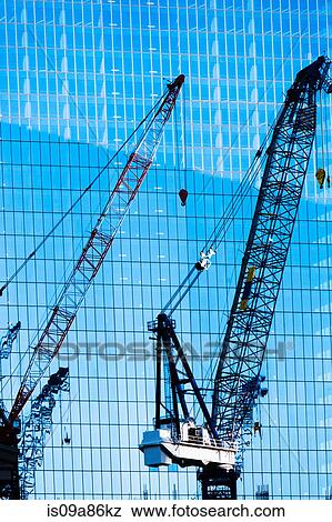 Stock Photo - Construction cranes in front of office building. Fotosearch