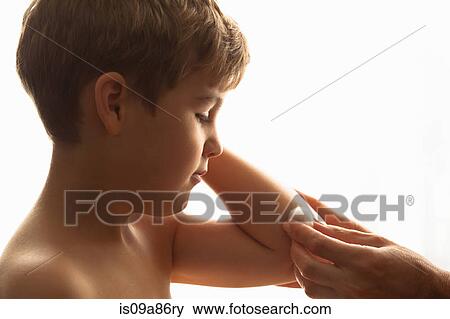 Stock Photo - Cropped shot of mother's hand cleaning son's elbow with cotton wool. Fotosearch