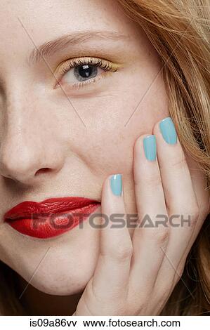Stock Photo - Cropped shot of young woman with curly red hair wearing make up, hand on chin. Fotosearch