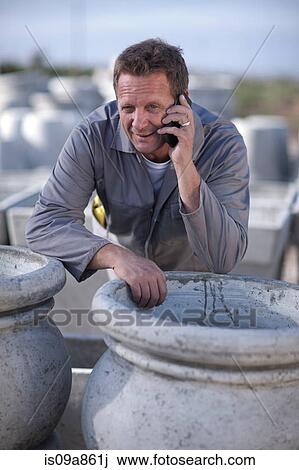 Stock Image - Factory worker talking on cellular phone. Fotosearch