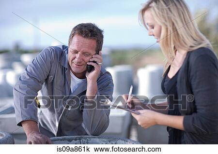 Stock Image - Factory worker talking on cellular phone. Fotosearch