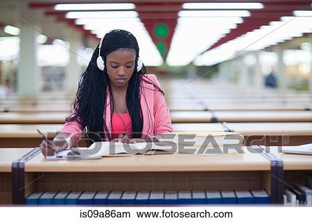 Picture - Female student studying in library. Fotosearch