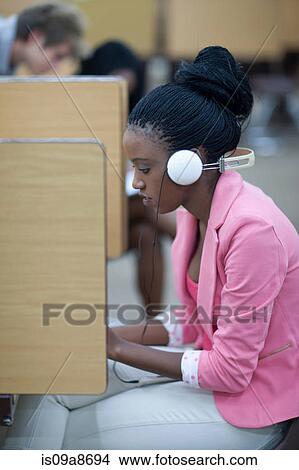 Female student working in library with headphones View Large Photo Image Picture - Female student working in library with headphones. Fotosearch