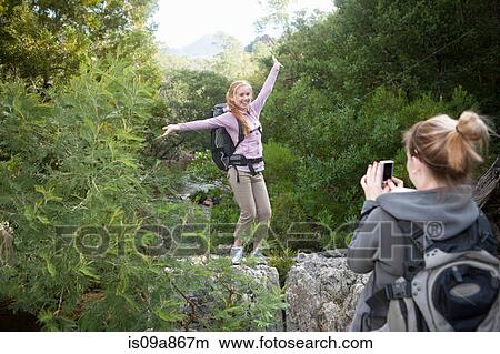 Picture - Girl hikers photographing each other on rock. Fotosearch