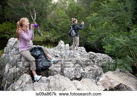 Stock Image - Girl hikers taking a break on rocks. Fotosearch