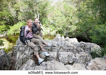 Stock Image - Girl hikers taking photographs from rock. Fotosearch