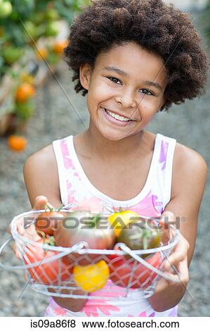 Stock Photo - Girl holding basket of ripe tomatoes. Fotosearch