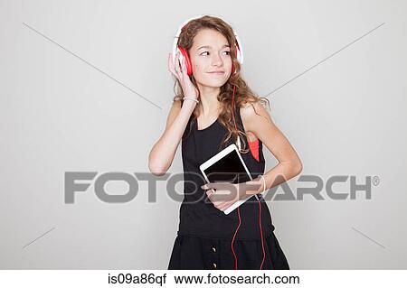 Stock Image - Girl holding digital tablet, wearing headphones. Fotosearch