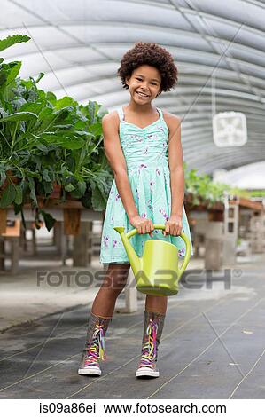 Stock Image - Girl holding green watering can. Fotosearch