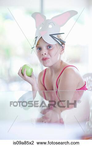 Stock Image - Girl in rabbit costume eating apple. Fotosearch