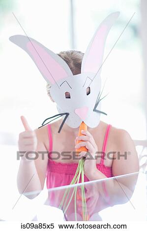 Stock Photography - Girl in rabbit costume eating carrot. Fotosearch
