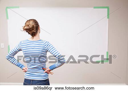 Stock Photography - Girl looking at blank space on wall. Fotosearch