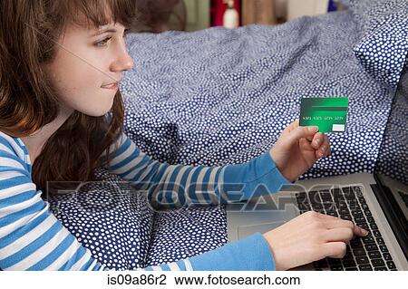 Girl lying on bed with laptop internet shopping View Large Photo Image Stock Image - Girl lying on bed with laptop internet shopping. Fotosearch