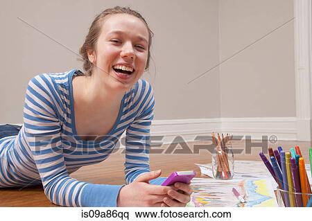 Girl lying on floor with smartphone and art materials View Large Photo Image Stock Photography - Girl lying on floor with smartphone and art materials. Fotosearch