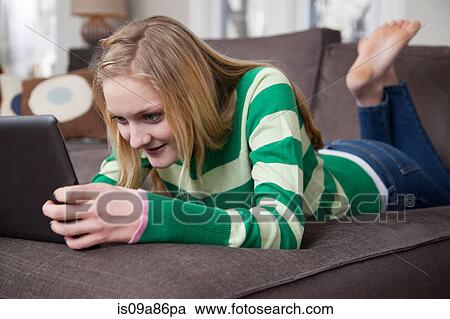 Girl lying on front using digital tablet View Large Photo Image Stock Image - Girl lying on front using digital tablet. Fotosearch