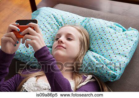 Girl lying on sofa playing handheld video game View Large Photo Image Stock Photography - Girl lying on sofa playing handheld video game. Fotosearch