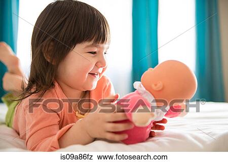 Girl playing with dolly in bedroom View Large Photo Image Stock Photo - Girl playing with dolly in bedroom. Fotosearch