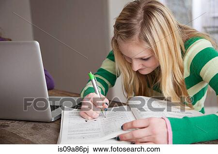 Stock Image - Girl sitting at table studying. Fotosearch