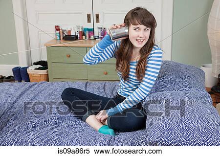 Girl sitting on bed playing with tin can telephone View Large Photo Image Stock Photography - Girl sitting on bed playing with tin can telephone. Fotosearch
