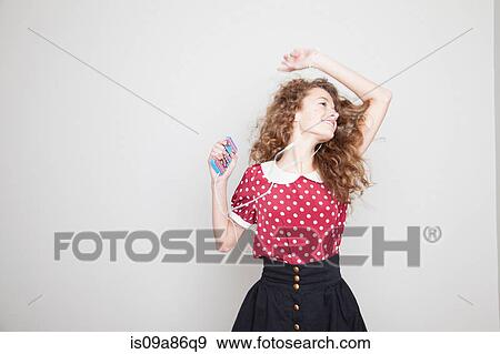 Stock Photo - Girl wearing headphones, dancing and holding mp3 player. Fotosearch