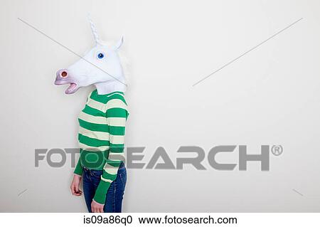 Stock Image - Girl wearing unicorn head. Fotosearch