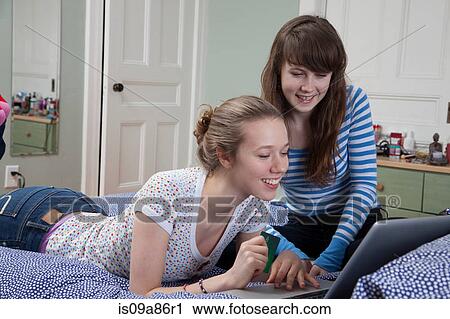 Girls lying on bed with laptop internet shopping View Large Photo Image Stock Image - Girls lying on bed with laptop internet shopping. Fotosearch