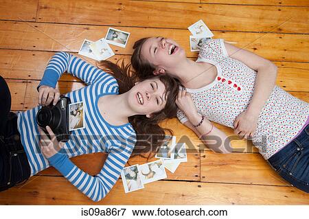 Girls lying on floor with camera, surrounded by photographs View Large Photo Image Stock Photo - Girls lying on floor with camera, surrounded by photographs. Fotosearch