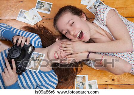 Girls lying on floor with camera, surrounded by photographs View Large Photo Image Stock Photograph - Girls lying on floor with camera, surrounded by photographs. Fotosearch