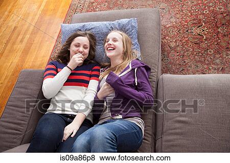 Stock Photo - Girls lying on sofa giggling. Fotosearch