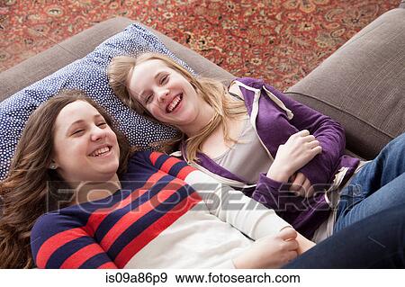 Girls lying on sofa giggling View Large Photo Image Stock Photo - Girls lying on sofa giggling. Fotosearch