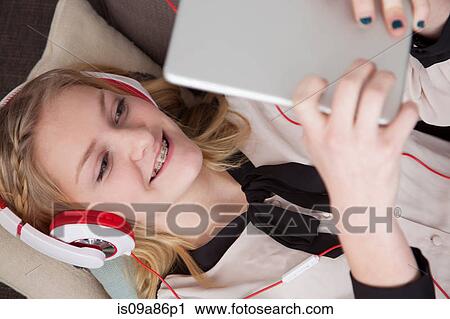 Girls lying on sofa using digital tablet View Large Photo Image Stock Image - Girls lying on sofa using digital tablet. Fotosearch