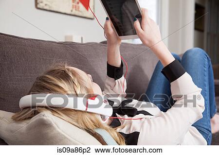 Stock Image - Girls lying on sofa using digital tablet. Fotosearch