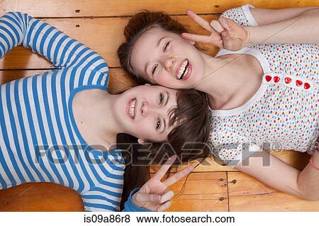 Girls lying on wooden floor doing peace signs View Large Photo Image Stock Photo - Girls lying on wooden floor doing peace signs. Fotosearch