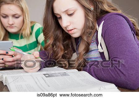 Stock Photograph - Girls sitting at table studying. Fotosearch