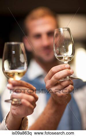 Stock Photography - Holding up wine glass to check colour of wine. Fotosearch