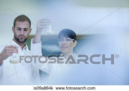 Stock Image - Laboratory technicians checking contents in laboratory beakers. Fotosearch