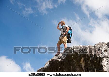 Male hiker standing on rock formation looking at view View Large Photo Image Stock Photo - Male hiker standing on rock formation looking at view. Fotosearch