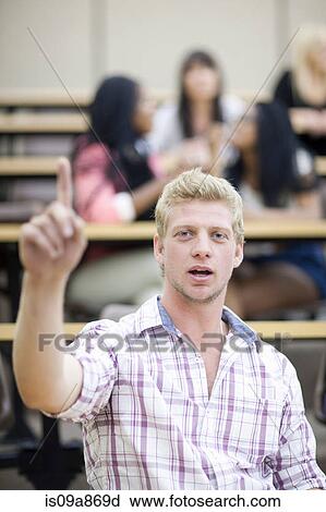 Stock Image - Male student in lecture with arm raised. Fotosearch