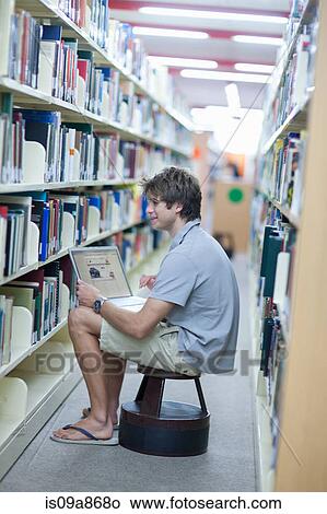 Male student using laptop in library View Large Photo Image Picture - Male student using laptop in library. Fotosearch