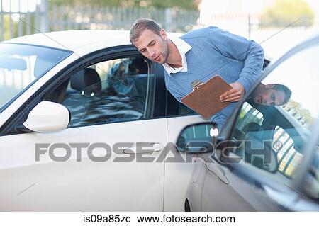 Stock Image - Man assessing damage on car after car accident. Fotosearch