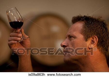 Stock Image - Man checking the color of red wine. Fotosearch