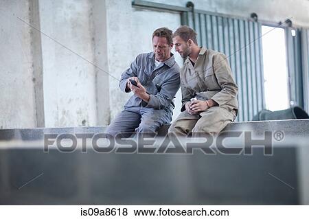 Stock Photo - Man showing something on smartphone to work colleague. Fotosearch