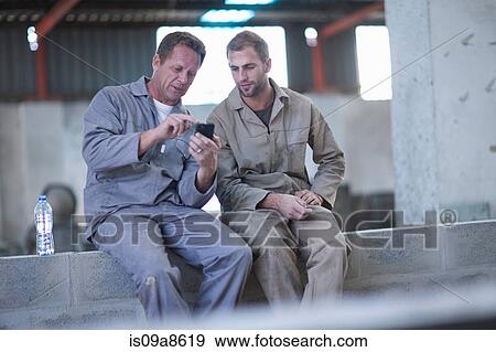 Stock Photo - Man showing something on smartphone to work colleague. Fotosearch