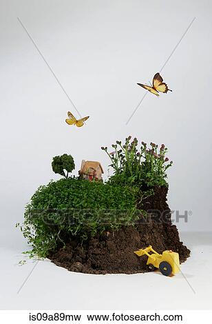 Stock Photo - Model of house on soil with digger and butterflies. Fotosearch