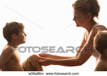Mother putting adhesive plaster on son's knee View Large Photo Image Stock Photo - Mother putting adhesive plaster on son's knee. Fotosearch